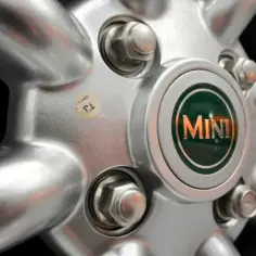 Zbliżenie na srebrną felgę Mini z widocznym logo i śrubami.