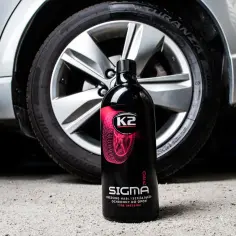 Butelka K2 Sigma z napisem "Dressing nabłyszczająco-ochronny do opon" obok koła samochodu. Idealny sposób, jak nabłyszczyć opony domowym sposobem.