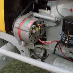 Szczegółowy widok alternatora i filtra oleju w ciągniku C-330. Pokazuje, jak podłączyć alternator do C-330, z widocznymi przewodami i mocowaniami.