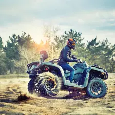 Mężczyzna w kasku jedzie quadem 250cc po piaszczystym terenie. Zastanawiasz się, jakie prawo jazdy na quada 250cc jest potrzebne?