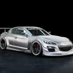 Srebrna Mazda RX8 z agresywnym body kitem, szerokimi błotnikami, spojlerem i felgami Toyo Tires.
