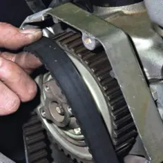 Dłoń mechanika napina pasek rozrządu na zębatce. To kluczowy moment, by wiedzieć jak ustawić rozrząd.