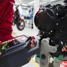 Osoba nalewa olej Motul do silnika motocykla. Pamiętaj o regularnej wymianie oleju, co ile km wymiana oleju w motocyklu zależy od modelu.