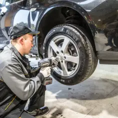 Mechanik używa klucza udarowego, by zdjąć zapieczone koło z podniesionego samochodu.