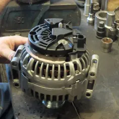 Mechanik pracuje nad regeneracją alternatora. Zastanawiasz się, ile trwa regeneracja alternatora? Proces ten zależy od stopnia uszkodzenia i dostępności części.