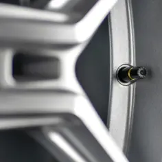 Szukasz informacji, jak dobrać wentyl do felgi? Zobacz zbliżenie na wentyl w srebrnej feldze aluminiowej.