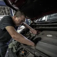 Mechanik sprawdza, jak sprawdzić wentylator chłodnicy na krótko, pracując przy silniku V6.