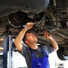 Mechanik wykonuje wymianę tulei wahacza bez prasy, używając klucza do precyzyjnego dopasowania części.