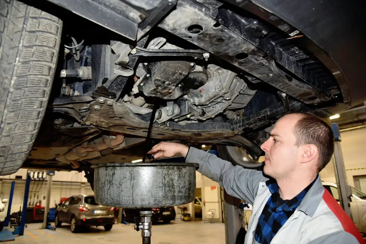 Mechanik spuszcza zużyty olej z samochodu. Dowiedz się, ile kosztuje wymiana oleju w samochodzie.