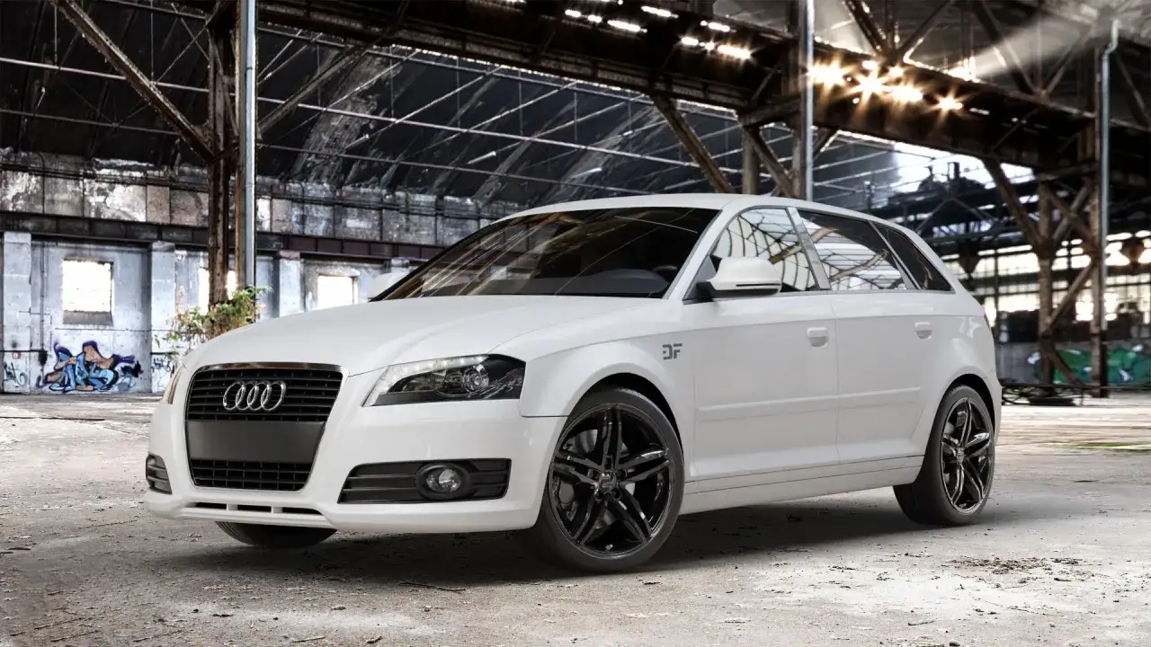 Białe Audi A3 8P z czarnymi felgami i subtelnym tuningiem optycznym, zaparkowane w opuszczonej hali przemysłowej.