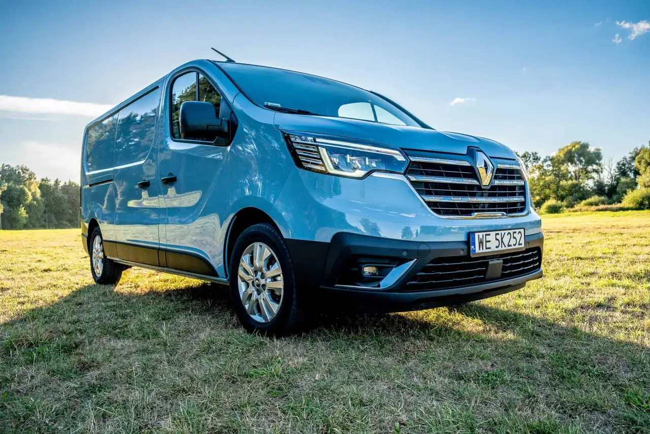 Jasnoniebieski Renault Trafic na trawie. Zastanawiasz się, jaki silnik wybrać do swojego Renault Trafic?