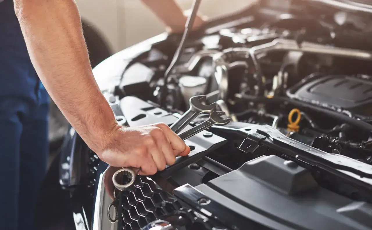 Mechanik z kluczami przy silniku. Zastanawiasz się, ile trwa regeneracja alternatora?
