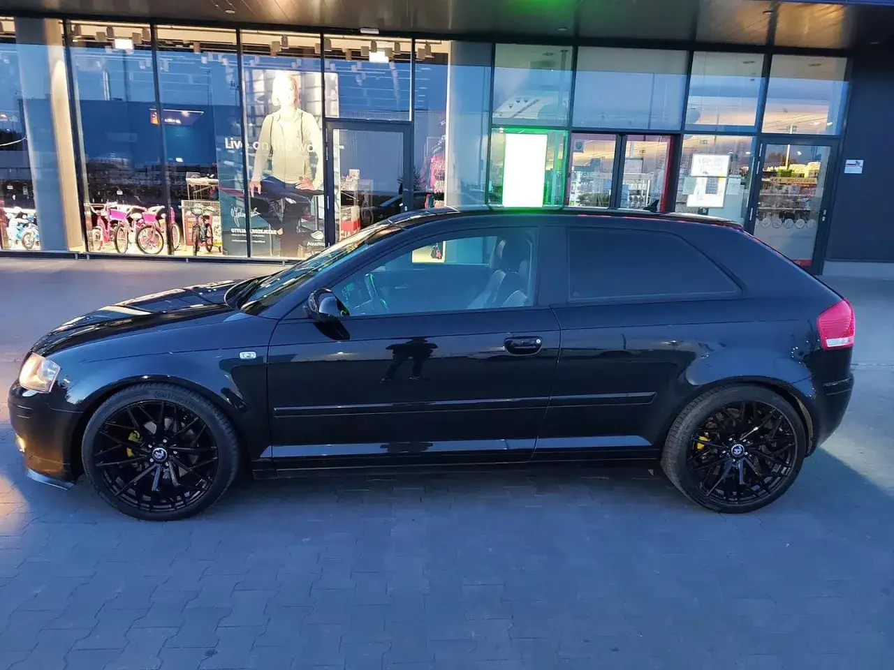 Czarny Audi A3 8P z tuningiem optycznym: przyciemnione szyby, czarne felgi i żółte zaciski hamulcowe.