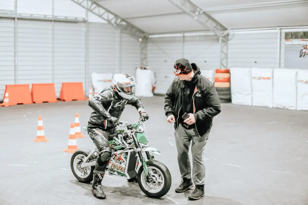 Instruktor tłumaczy młodemu motocykliście, jak hamować motocyklem, podczas treningu na torze.