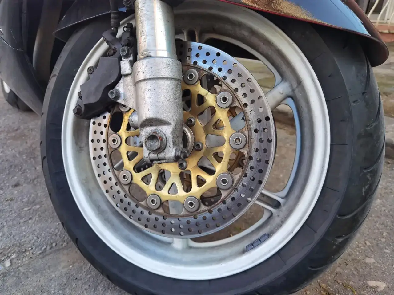 Przednia tarcza hamulcowa motocykla z zaciskiem i felgą. Kluczowy element, by wiedzieć, jak hamować motocyklem.