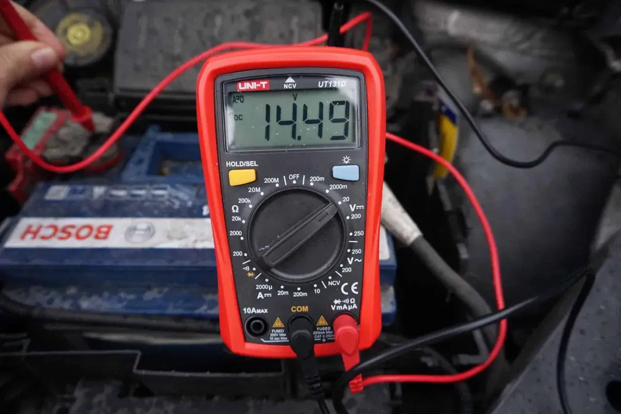 Pomiar napięcia akumulatora multimetrem, wskazanie 14.49V. To jeden ze sposobów, jak sprawdzić regulator napięcia w alternatorze.
