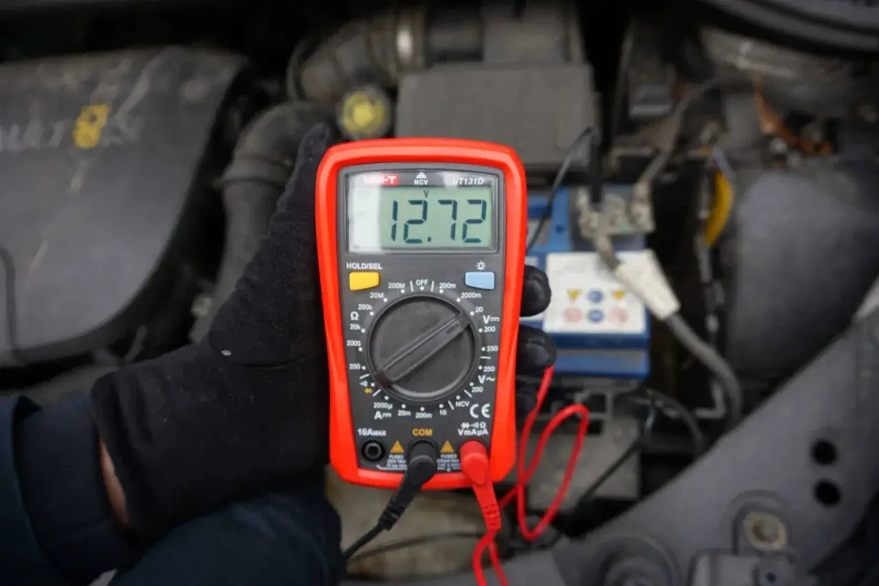 Multimetr pokazuje 12.72V, sprawdzając, czy alternator ładuje akumulator na postoju.