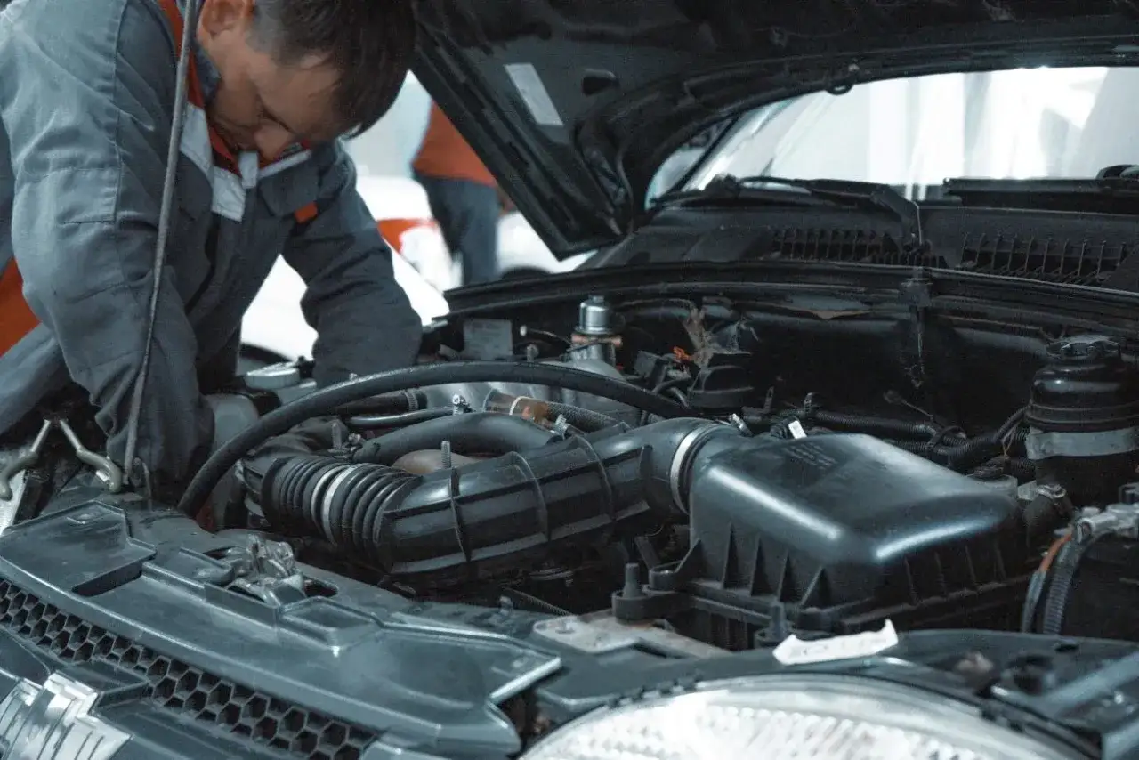 Mechanik pracuje przy silniku, sprawdzając, ile kosztuje wymiana oleju w samochodzie.