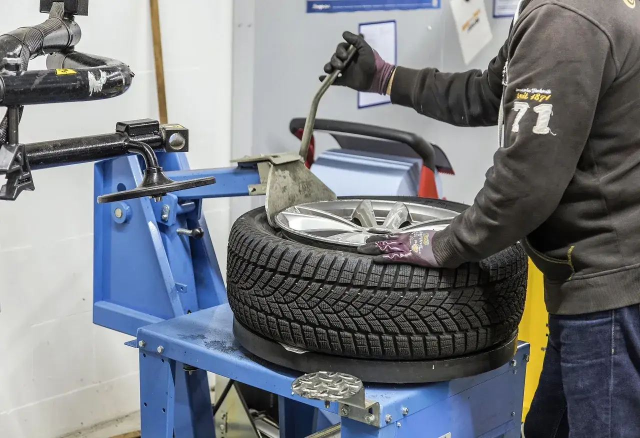 Mechanik w warsztacie wymienia oponę na maszynie. Szybko dowiedz się, ile zajmuje wymiana opon.
