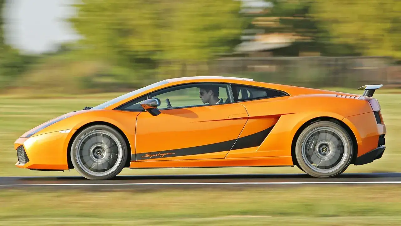 Pomarańczowe Lamborghini Gallardo Superleggera w ruchu. Zastanawiasz się, ile kosztuje lamborghini gallardo?