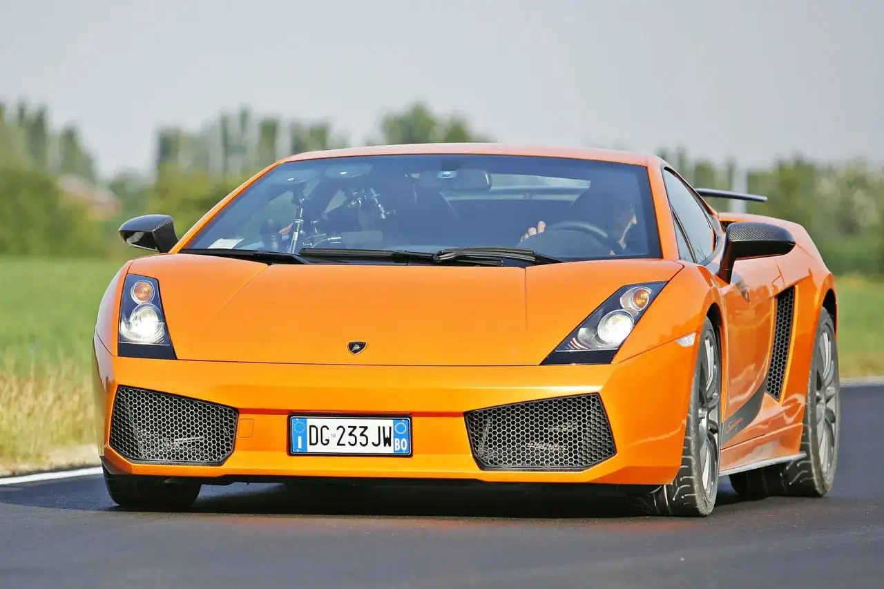 Pomarańczowe Lamborghini Gallardo na drodze. Zastanawiasz się, ile kosztuje lamborghini gallardo?